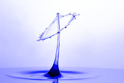 Close-up of water drop on glass against white background