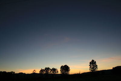 Silhouette trees on landscape against sky at sunset