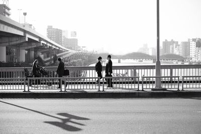 Man on bridge over river in city against clear sky