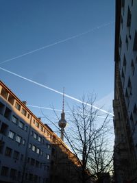 Low angle view of vapor trail in city against sky