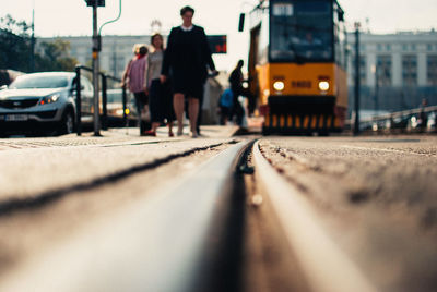 Surface level of people walking by tram on railroad tracks