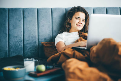 Young woman using mobile phone while sitting on sofa at home