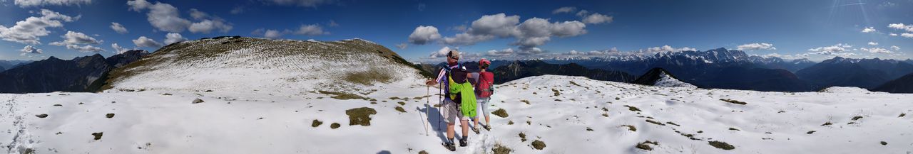 Panoramic shot of couple standing on snowcapped mountain