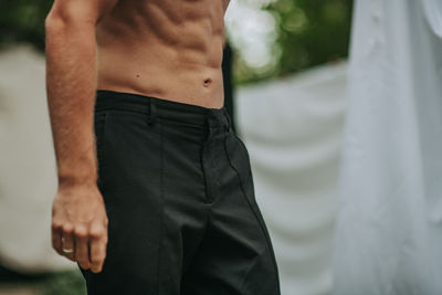 Midsection of shirtless man standing against blurred background