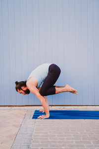 Side view of man doing handstand against wall