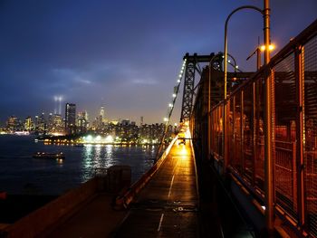 Illuminated bridge over river amidst buildings in city at night