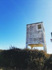 Low angle view of abandoned built structure against blue sky