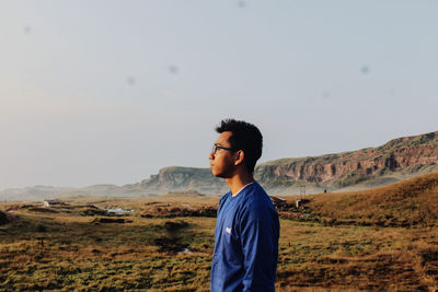 Young man standing on mountain against sky