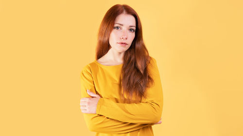 Young woman standing against yellow background