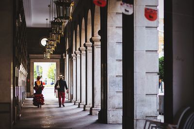 Rear view of two people walking on corridor