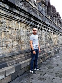 Full length of young man standing against old wall