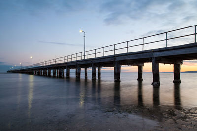 Bridge over sea against sky at sunset