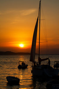 Silhouette sailboats in sea against sky during sunset