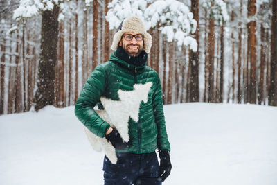 Portrait of smiling woman standing on snow covered land