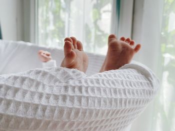 Low section of person relaxing on bed at home