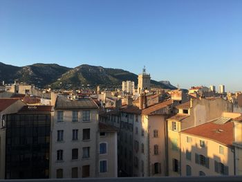 Buildings in city against clear blue sky