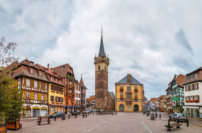 View of buildings in city against cloudy sky