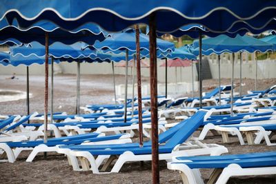 Empty chairs at beach against blue sky