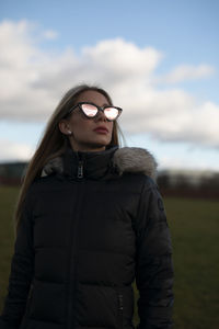 Portrait of young woman standing against sky