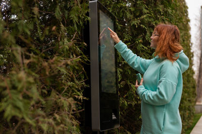 Side view of woman using kiosk