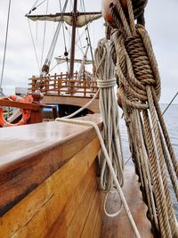 Sailboat tied to wooden post in sea against sky