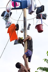 Low angle view of people hanging against sky