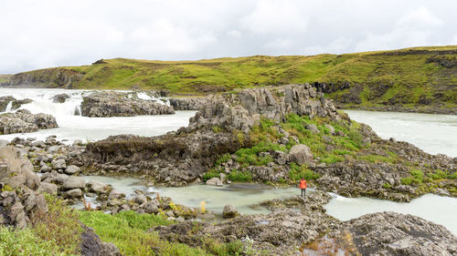 Bright hiker is crossing the white water creek in iceland