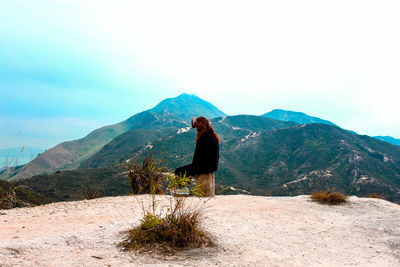 Rear view of woman standing on mountain against sky