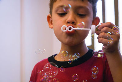 Close-up boy blowing bubbles at home