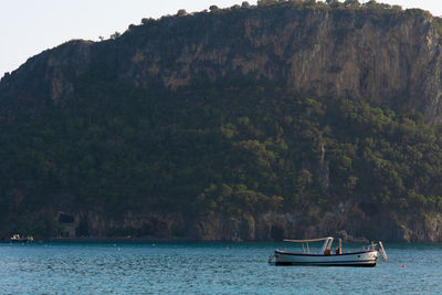 Boat sailing on sea against mountains