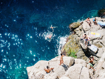 High angle view of people on rock over sea