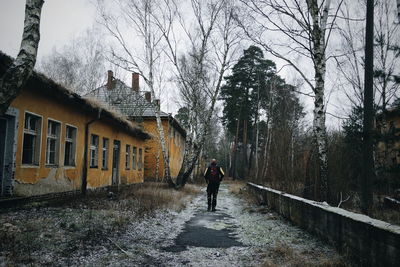 Man walking on street amidst trees against sky