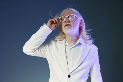 Portrait of young woman standing against black background