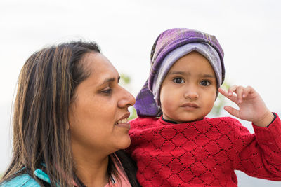 Portrait of mother and daughter against clear sky
