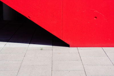 Shadow on footpath against red wall