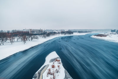 Scenic view of frozen river against sky in city