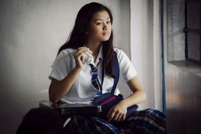 Young woman sitting on book at home