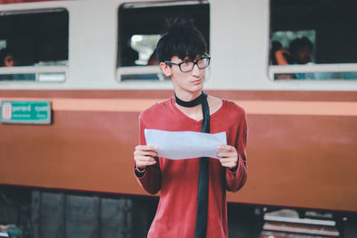 Portrait of young man standing against wall