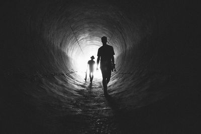 Rear view of silhouette men walking in tunnel