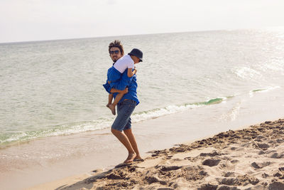 Dad and son play on the beach in summer in blue clothes while on vacation