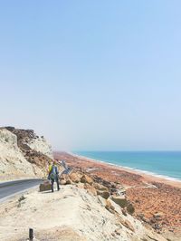 Man walking at beach against clear sky