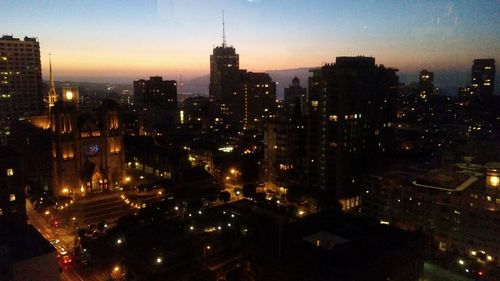 Illuminated cityscape against sky at dusk