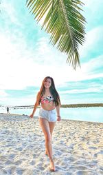 Portrait of woman standing at beach against sky