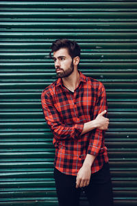 Portrait of young man standing against wall