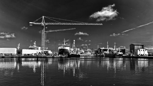 Crane and boats at harbor on sea against sky