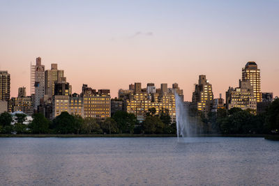 Modern buildings in city against sky during sunset