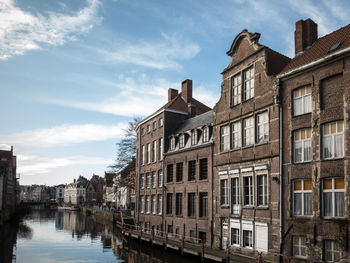 Buildings by canal against sky