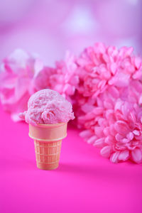 Close-up of ice cream with flowers against pink background