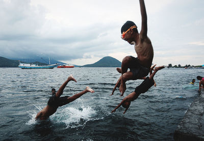 Rear view of man jumping in sea against sky