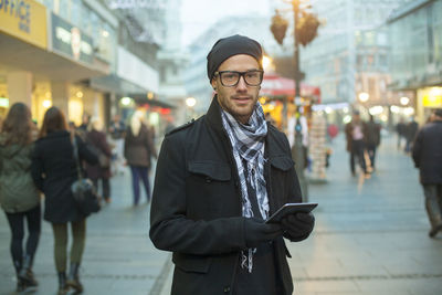 Portrait of young man standing on street in city